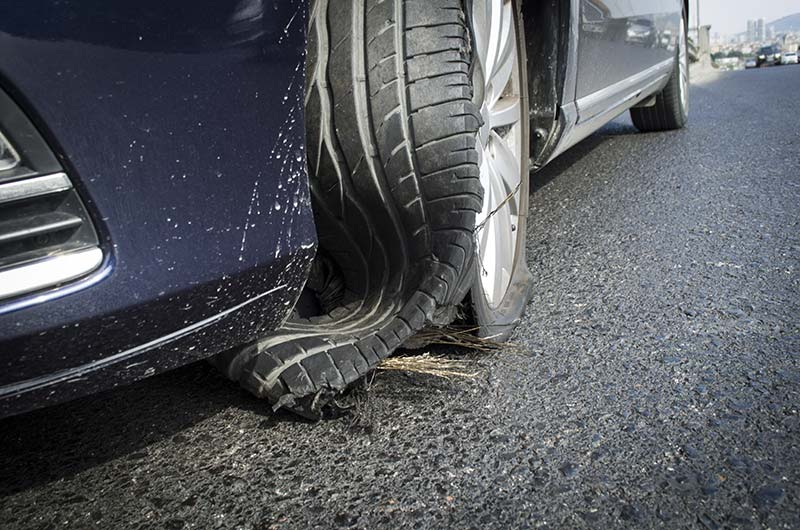 Close-up of a damaged car tire after hitting a pothole on a city street